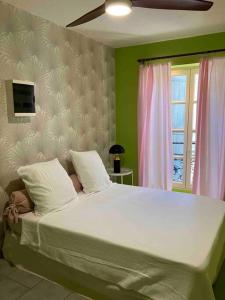 a bedroom with a large white bed with a window at Appartement Ibiz’Arles in Arles
