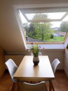 una mesa con un jarrón de flores delante de una ventana en Wohnung mit Stil en Troisdorf