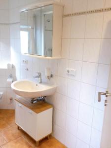 een witte badkamer met een wastafel en een spiegel bij Wohnung mit Stil in Troisdorf