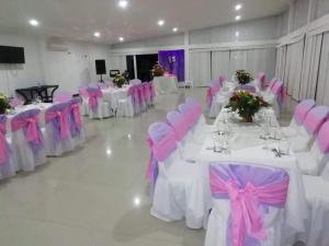 einen Bankettsaal mit weißen Tischen und rosa Stühlen in der Unterkunft Hotel Yakuana in Puerto López