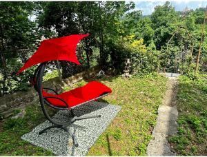 a red chair with an umbrella sitting in the grass at 0-A Diamond in Yonkers, NY in Yonkers