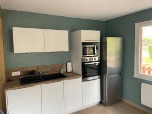 a kitchen with white cabinets and a stainless steel refrigerator at Chalet Le Cèdre Bleu 10 p - 10 min de Gérardmer in Le Tholy