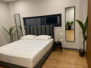 1 dormitorio con 1 cama blanca grande y espejo en Rosemarine Villas, en Durrës