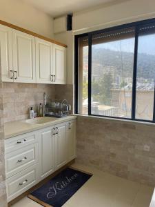 kuchnia z białymi szafkami i dużym oknem w obiekcie Estrela Mares Haifa w mieście Hajfa