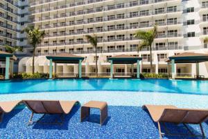 a large swimming pool with chairs and a building at Shell Residence Manila in Manila
