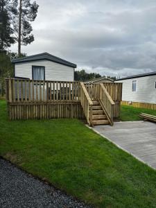 a wooden fence in a yard next to a house at Fairway 6 Lilliardsedge Caravan Hire in Jedburgh