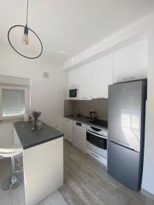 a kitchen with white cabinets and a refrigerator at Vila Oaza in Trebinje