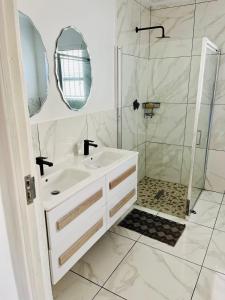 ein weißes Bad mit einem Waschbecken und einer Dusche in der Unterkunft Petalsoft in Pretoria