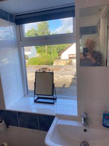 a woman taking a picture of a mirror in a bathroom at Aberlour Apartment 92 B in Aberlour
