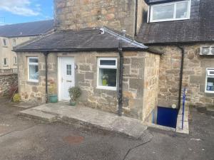 a stone house with a white door and a window at Aberlour Apartment 92 B in Aberlour