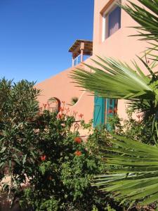 un bâtiment rose avec des plantes devant lui dans l'établissement Les Tourmalines, à Ouarzazate