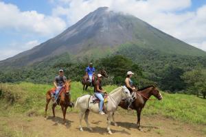 four people riding horses in front of a mountain at Arenal Observatory Lodge & Spa in Fortuna