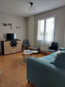 ein Wohnzimmer mit einem Sofa und einem TV in der Unterkunft MaMaMé in Les Sables-dʼOlonne