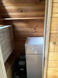 einen kleinen weißen Kühlschrank in einem Zimmer mit Holzwänden in der Unterkunft Chatka pod lasem in Jarnołtówek