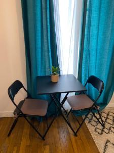 a table and two chairs in front of a window at Joli petit 2 pièces in Asnières-sur-Seine