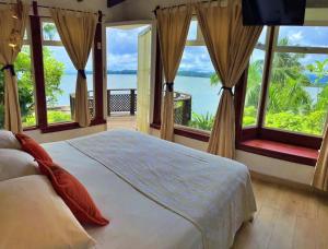 a bedroom with a bed with a view of the water at Villa Caribe in Lívingston