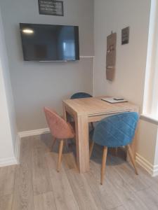 a wooden table with two chairs and a television on a wall at Flat 5 Corner House 1 bedroom in Doncaster