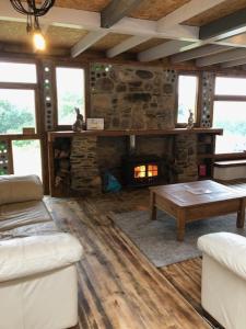 een woonkamer met een stenen open haard en een bank bij Rabbits 1or 2 bedroom hobbit style hillset earthen dartmoor eco home in South Brent