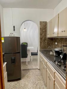 Una cocina con refrigerador de acero inoxidable y una mesa. en Hermoso apartamento en zona central de Medellín, en Medellín