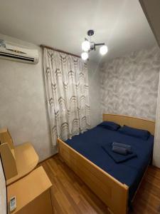 une chambre avec un lit bleu et une fenêtre dans l'établissement Apartment in Yerevan, on Margaryan street, à Erevan