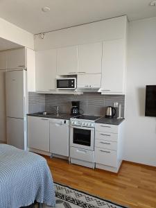 Una cocina con gabinetes blancos y un horno de estufa. en Sunstar Apartments, en Rovaniemi