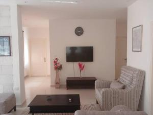 Zara's luxury Home- central location near Abdali في عمّان: غرفة معيشة مع كرسيين وتلفزيون بشاشة مسطحة