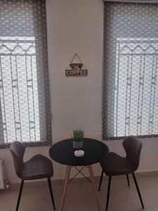 Zara's luxury Home- central location near Abdali في عمّان: طاولة وكرسيين في غرفة بها نافذتين