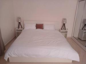 sypialnia z białym łóżkiem i 2 szafkami nocnymi w obiekcie Zara's luxury Home- central location near Abdali w mieście Amman