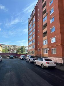 a parking lot with cars parked in front of a building at Современная квартира в центре города in Kostanay