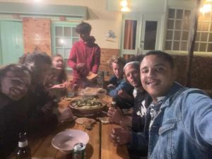 un grupo de personas sentadas alrededor de una mesa comiendo comida en WEST COAST HOSTEL en Imsouane