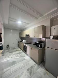 uma grande cozinha com armários e electrodomésticos brancos em Recidence montblanc Tanger em Tânger