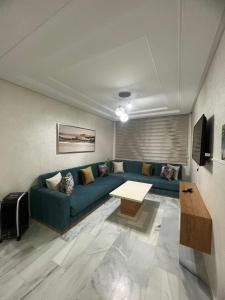 uma sala de estar com um sofá azul e uma mesa em Recidence montblanc Tanger em Tânger