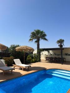 a swimming pool with two chairs and an umbrella at Surf&fun heated pool villa in La Oliva