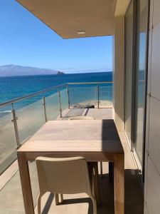 a wooden table and chairs on a balcony with the ocean at Lazareto Oceanview in Mindelo