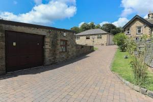a brick building with a garage and a brick driveway at Wend Gardens, Carleton, Skipton. Pet friendly. in Skipton
