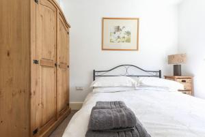 a bedroom with a large white bed with a wooden cabinet at Wend Gardens, Carleton, Skipton. Pet friendly. in Skipton