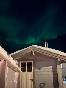 una casa con las verdes luces del norte en el cielo en Leilighet i Vadsø en Vadsø