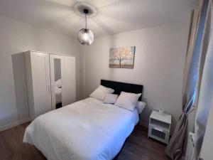 - une chambre avec un grand lit blanc et une lampe dans l'établissement APPartement 15 minutes de paris 2 bedrooms, à Drancy