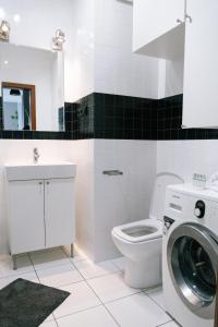 a bathroom with a toilet and a washing machine at Żoliborz Business Apartments by Rentujemy in Warsaw