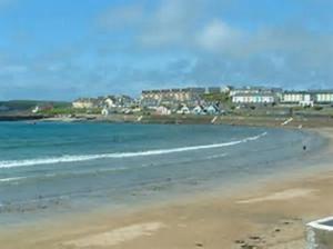 een strand met een stad op de achtergrond en de oceaan bij Ann & Andy in Kilkee