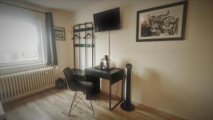 Zimmer mit einem Schreibtisch, einem Stuhl und einem TV in der Unterkunft Roastineer Hotel in Battenberg