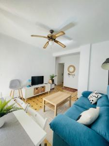 sala de estar con sofá azul y ventilador de techo en CASATUN Santapolera en Playa de Levante en Santa Pola