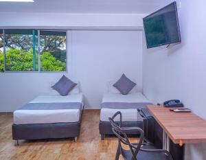 Habitación con 2 camas y escritorio con ordenador. en Hotel Palmas del Estadio, en Medellín