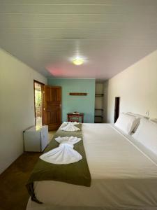 a bedroom with a large white bed with towels on it at Pousada Jambrero in Caraíva