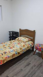 a bedroom with a bed with a comforter and a chair at Apartamento com 3 quartos! 7 camas no Centro in Lages