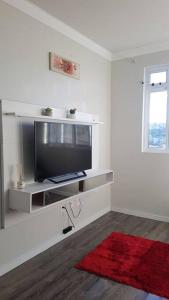 a living room with a television and a red rug at Apartamento com 3 quartos! 7 camas no Centro in Lages