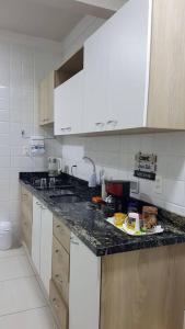 a kitchen with white cabinets and a black counter top at Apartamento com 3 quartos! 7 camas no Centro in Lages