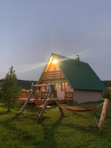 ein Haus mit einem grünen Dach und einer Person, die davor steht in der Unterkunft Planinska kuca in Žabljak