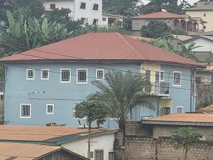 MediSweet Apartments Meublés في ياوندي: منزل ازرق بسقف احمر فوق المنازل