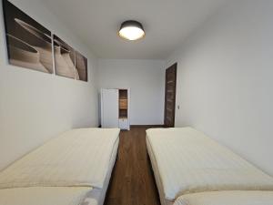 two beds in a room with white walls at Apartmán U Labe in Nymburk